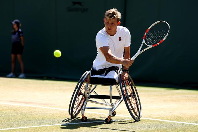 A male wheelchair tennis player returns a backhand shot